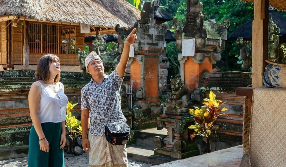A tourist walking through a Bali villages guided by a local resident, learning about daily life and traditions.