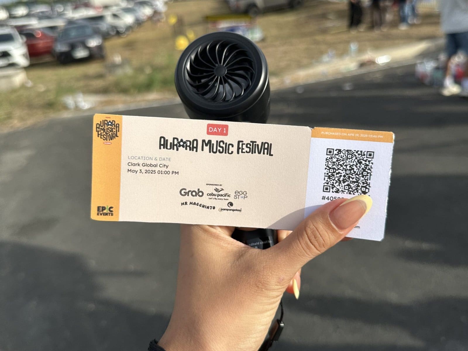 Hand holding an Aurora Festival ticket at the Clark, Pampanga venue, ready for the night of live Filipino music and adventure.